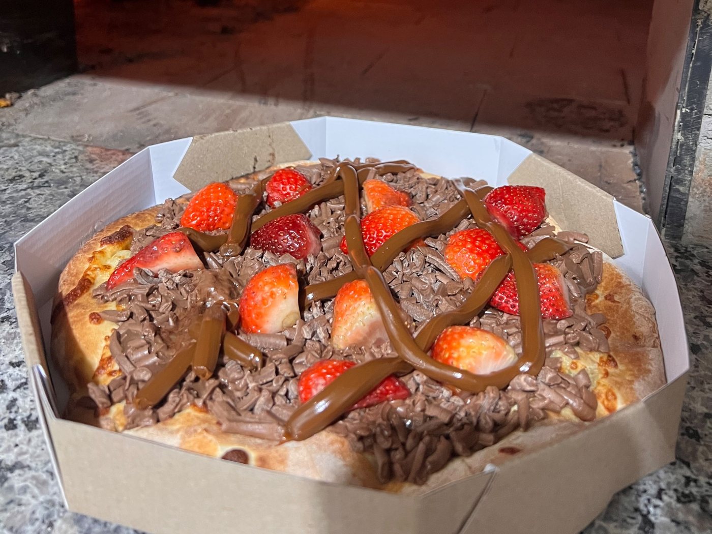 Pizza doce de chocolate com morango, na caixa